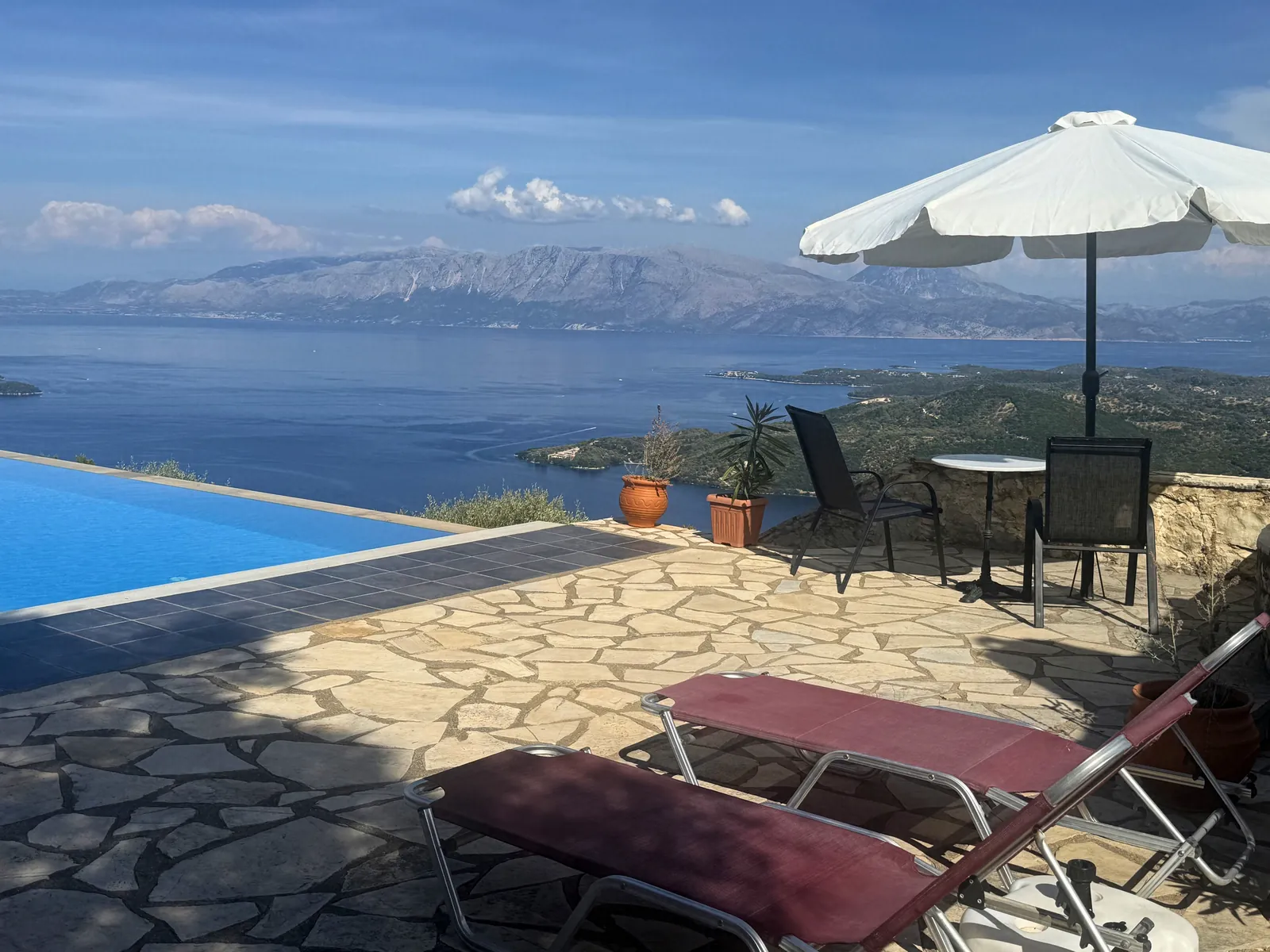 Ξαπλώστρες και ομπρέλα δίπλα στην πισίνα